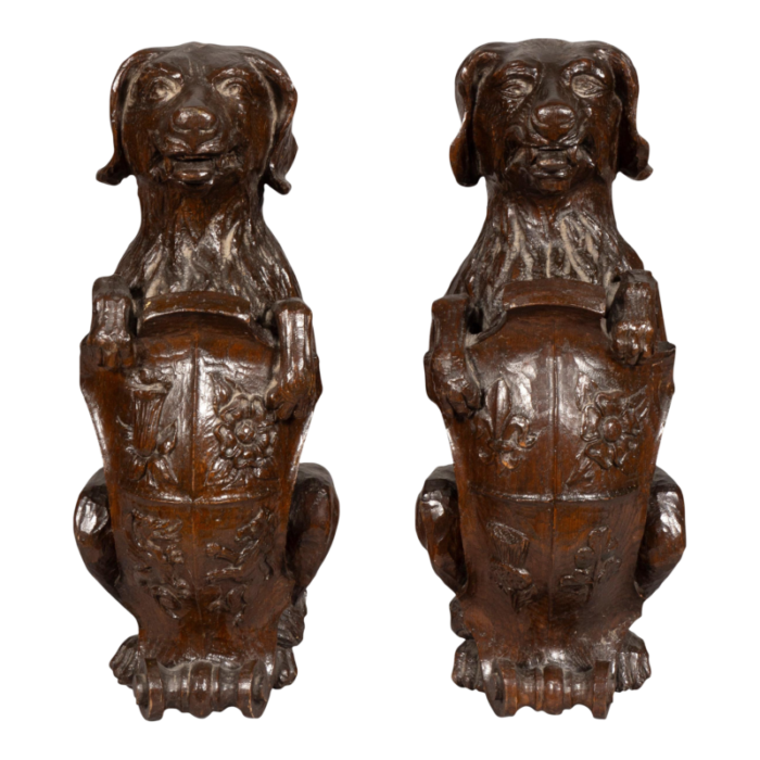 carved oak figures of seated dogs with shields a pair 9235